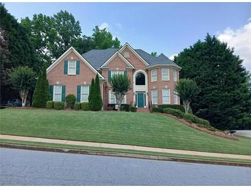 Traditional two-story brick home with green shutters, manicured lawn, and mature trees at 1564 Stepstone Way, Lawrenceville, GA 30043