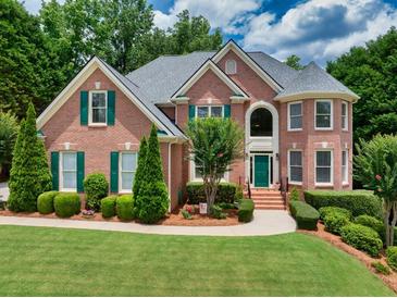 Charming brick home featuring manicured landscaping, green shutters, and a turret-style entryway, all under a blue sky at 1564 Stepstone Way, Lawrenceville, GA 30043