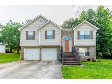 Two-story home featuring a two-car garage, tan siding, brick accents, and a well-manicured front lawn at 3617 Summit Trce, Decatur, GA 30034