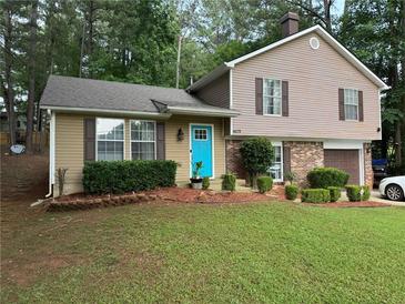 Charming two-story home with a well-maintained lawn, tidy landscaping, and a bright blue front door at 4678 Browns Mill Ferry Rd, Lithonia, GA 30038