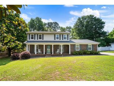 Charming two-story home featuring a covered front porch with rocking chairs and a lush green lawn at 385 Stonebridge Trl, Roswell, GA 30075