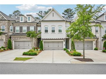 Beautiful townhome featuring a brick facade and a two-car garage with manicured landscaping at 20056 Windalier Way, Roswell, GA 30076