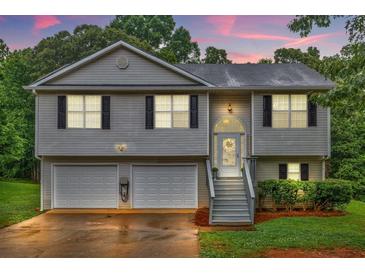 Charming split-level home featuring a two-car garage and inviting front porch at sunset at 240 Mountain Ln, Covington, GA 30016