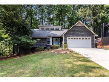 Charming home featuring a two-car garage and a well-manicured lawn, nestled amidst lush trees, and with a light blue front door at 2960 Cedar Knoll Dr, Roswell, GA 30076