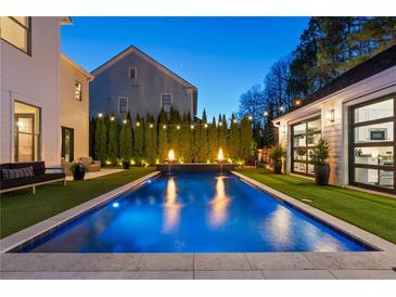 Stunning backyard pool featuring elegant water features, manicured landscaping, and ambient lighting at 7165 Cordery Rd, Cumming, GA 30040