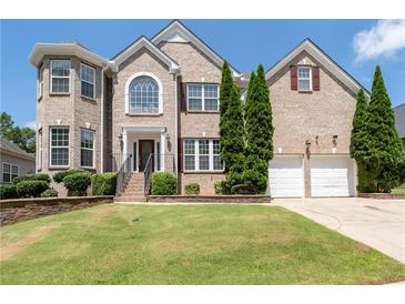 Beautiful two-story brick home featuring a manicured lawn, trimmed shrubbery, and a two-car garage at 3717 Shady Maple Dr, Stonecrest, GA 30038