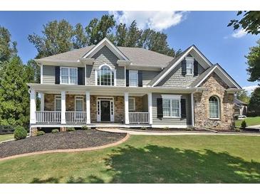 Charming two-story home with a manicured lawn, inviting front porch, and stone accents at 6425 Riley Manor Way, Cumming, GA 30028