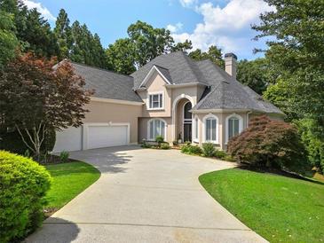 Stately home with a three-car garage and elegant circular driveway surrounded by mature trees and lush landscaping at 9745 Autry Falls Dr, Alpharetta, GA 30022