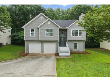 Charming home with gray siding, stone accents, two-car garage and well-maintained lawn at 11020 Knotty Pine Pl, Hampton, GA 30228