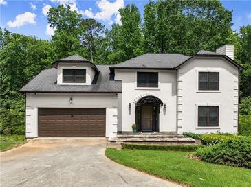 Elegant two-story home with a brown garage door, manicured lawn, and mature trees at 130 Timber Oak Cv, Lawrenceville, GA 30043