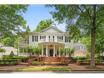 Charming two-story traditional home featuring a brick porch with columns and double-decker balconies nestled in a lush landscape at 8643 Ellard Dr, Alpharetta, GA 30022