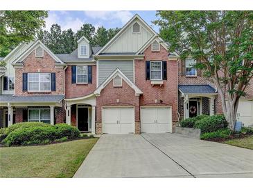 Charming brick townhome featuring an attached two-car garage and a well-manicured lawn at 1102 Lexington Dr, Roswell, GA 30075