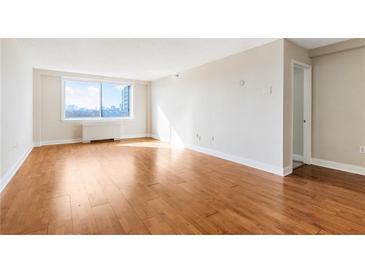 Bright, empty living room features hardwood floors and a large window with city views at 2479 Peachtree Ne Rd # 605, Atlanta, GA 30305