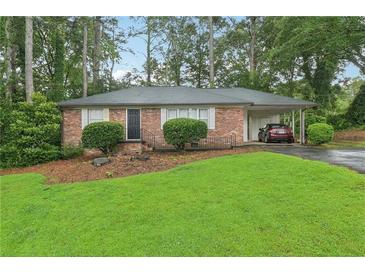 Charming brick home featuring a well-manicured lawn and lush landscaping, complete with an attached carport at 1849 Clay Sw Rd, Mableton, GA 30126