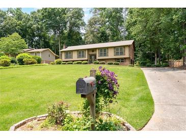 Charming home with a lush green lawn, mature trees, and a welcoming mailbox adorned with purple flowers at 272 Creek Sw Ct, Marietta, GA 30064