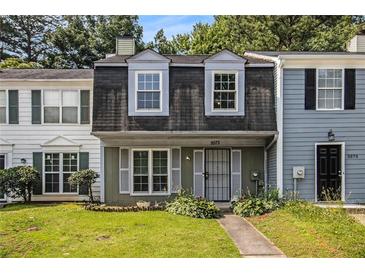 Charming townhome featuring a well-maintained lawn and a classic front entrance with shuttered windows at 5575 Wells Circle, Stone Mountain, GA 30087