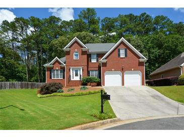 Charming two-story red brick home with a well-manicured lawn, mature trees, and two-car garage at 1703 Rifle Sw Rdg, Marietta, GA 30064