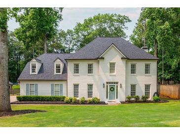 Elegant white brick home featuring a well-manicured lawn and charming blue shutters nestled among mature trees at 2735 Jims Ne Rd, Marietta, GA 30066