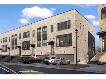 Modern townhome exterior featuring a brick facade, private garages, and manicured landscaping at 3208 Sonnet Se Walk, Atlanta, GA 30339