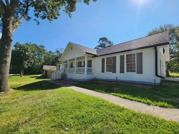 Charming white home featuring a welcoming porch, well-kept lawn, and beautiful, mature trees at 2136 Briarwood Ct, Snellville, GA 30078
