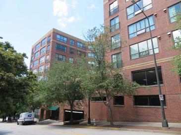 Exterior view of a red brick building with many windows and some trees in front on a partly cloudy day at 115 W Peachtree Nw Pl # 702, Atlanta, GA 30313