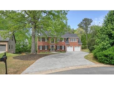 Inviting two-story red brick home featuring a two-car garage and a long driveway at 3130 Crestmont Nw Way, Kennesaw, GA 30152