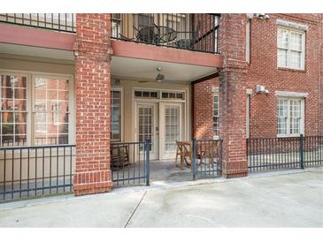 Brick condo patio with chairs, wrought iron fence, and double doors to interior at 1735 Peachtree Ne St # 117, Atlanta, GA 30309