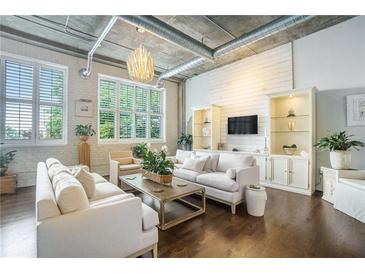 Bright, open living space with exposed pipes, hardwood floors, and large windows allowing natural light to flood in at 3235 Roswell Ne Rd # 402, Atlanta, GA 30305