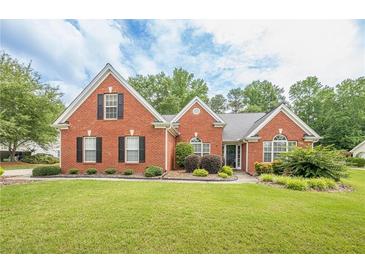 Charming brick home with a lush green lawn and manicured landscaping at 2870 Jay Oak Dr, Dacula, GA 30019