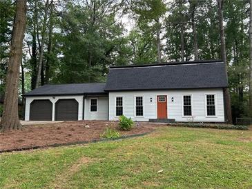 Charming single-story home with a two-car garage, orange front door, and a well-maintained lawn with mature trees at 4617 Cedar Park Dr, Stone Mountain, GA 30083