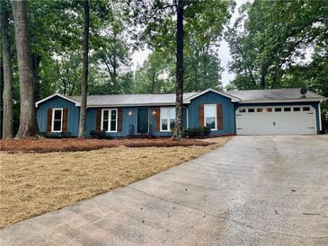 Charming single-story home boasts a lush green landscape, complemented by a spacious driveway and an attached garage at 1743 Moss Dr, Snellville, GA 30078
