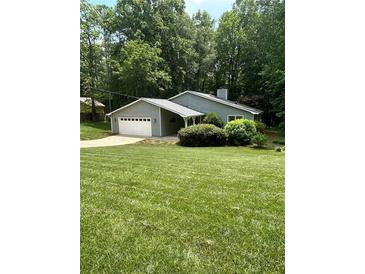 Charming single-story home featuring an attached garage, well-maintained lawn, and mature trees at 4766 Jamerson Forest Cir, Marietta, GA 30066