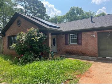 Cozy brick home featuring a charming front porch and solar panels at 1130 Monfort Rd, Lawrenceville, GA 30046