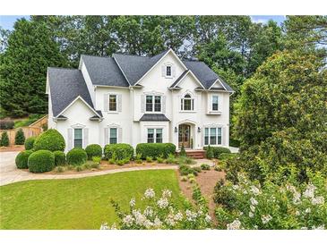 Stunning two-story white home with lush landscaping, offering timeless elegance and curb appeal at 505 Woodmoore Ct, Sandy Springs, GA 30342