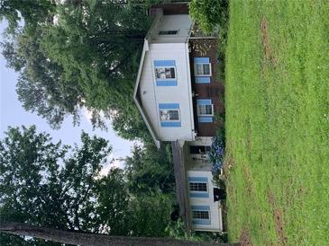 Charming home featuring white siding, blue shutters, and lush green lawn surrounded by mature trees at 2505 King Louis Rd, Conyers, GA 30012