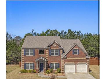 Charming two-story brick home featuring blue shutters, a well-manicured lawn and an attached two-car garage at 403 Sonja Ln, Loganville, GA 30052