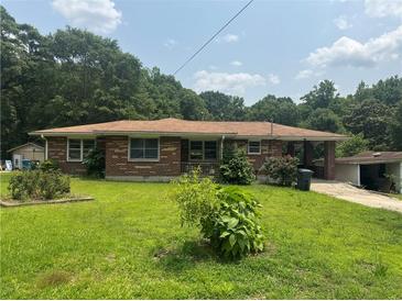 Quaint brick home featuring large front yard, small shrubs, and a covered carport with a small building nearby at 547 Morningside Dr, Lawrenceville, GA 30043
