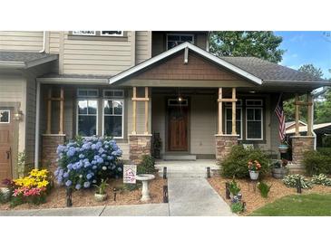 Charming front porch with stone accents, complemented by lush landscaping and a welcoming wood front door at 1268 Harris Road Rd, Lawrenceville, GA 30043