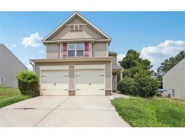 Charming two-story home with vinyl siding, a two-car garage, and manicured lawn at 7099 Skippingstone Way, Douglasville, GA 30134