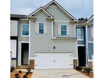 Charming townhome featuring a two-car garage and neutral siding with decorative shutters at 776 Woodstock Grove Dr, Woodstock, GA 30188