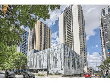 Modern high-rise building featuring glass facade and urban landscaping with tree line at 1280 W Peachtree Nw St # 3514, Atlanta, GA 30309