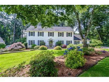Charming two-story home showcasing a beautifully landscaped front yard with lush greenery and vibrant flowers at 4714 Marc Sw Ct, Lilburn, GA 30047