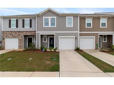 Charming townhomes featuring individual garages, landscaped lawns, and inviting front entrances at 124 Saginaw Ct, Locust Grove, GA 30248