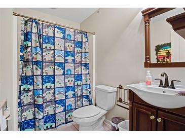 Cozy bathroom featuring a quirky shower curtain, single sink vanity and an updated toilet at 561 Holland Rd, Dallas, GA 30157