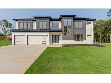 Modern two-story home featuring a spacious three-car garage and a lush green lawn at 52 Deer Canyon Dr, Auburn, GA 30011