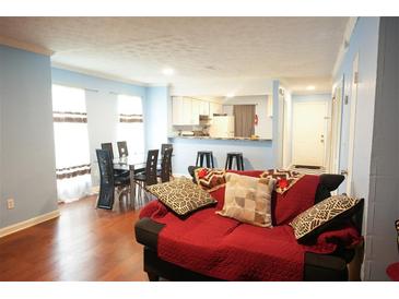 Inviting living room featuring a comfortable red sofa, an open kitchen, and a dining area with a black table and chairs at 852 Glynn Oaks Dr, Clarkston, GA 30021