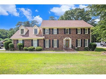 Charming two-story brick home with manicured lawn, dormer windows, and classic black shutters at 4837 Mystere Sw Cir, Lilburn, GA 30047