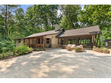 Charming single-story home featuring a large drive and outdoor seating area surrounded by lush greenery at 4025 Demooney Rd, Atlanta, GA 30349