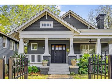 Charming craftsman home featuring a covered porch with white columns and a well-maintained landscaped yard and iron gate at 327 6Th Ne St, Atlanta, GA 30308