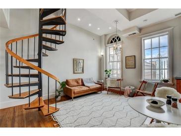 Bright living room featuring a spiral staircase, hardwood floors, and large windows with city views at 30 5Th Ne St # 1006, Atlanta, GA 30308